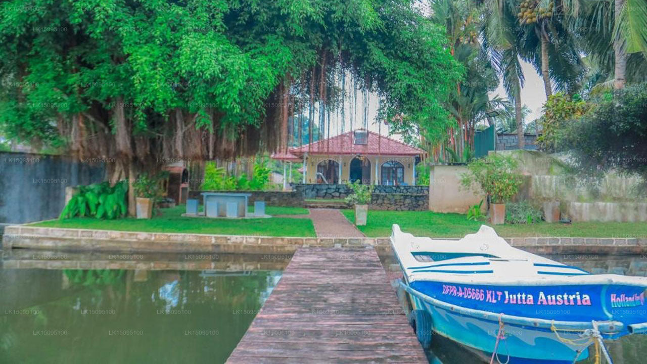 Boat docked by a calm body of water with greenery and a building in the background
