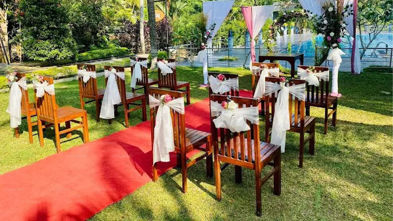 Decorated outdoor wedding setup with chairs, red carpet, and floral arches.
