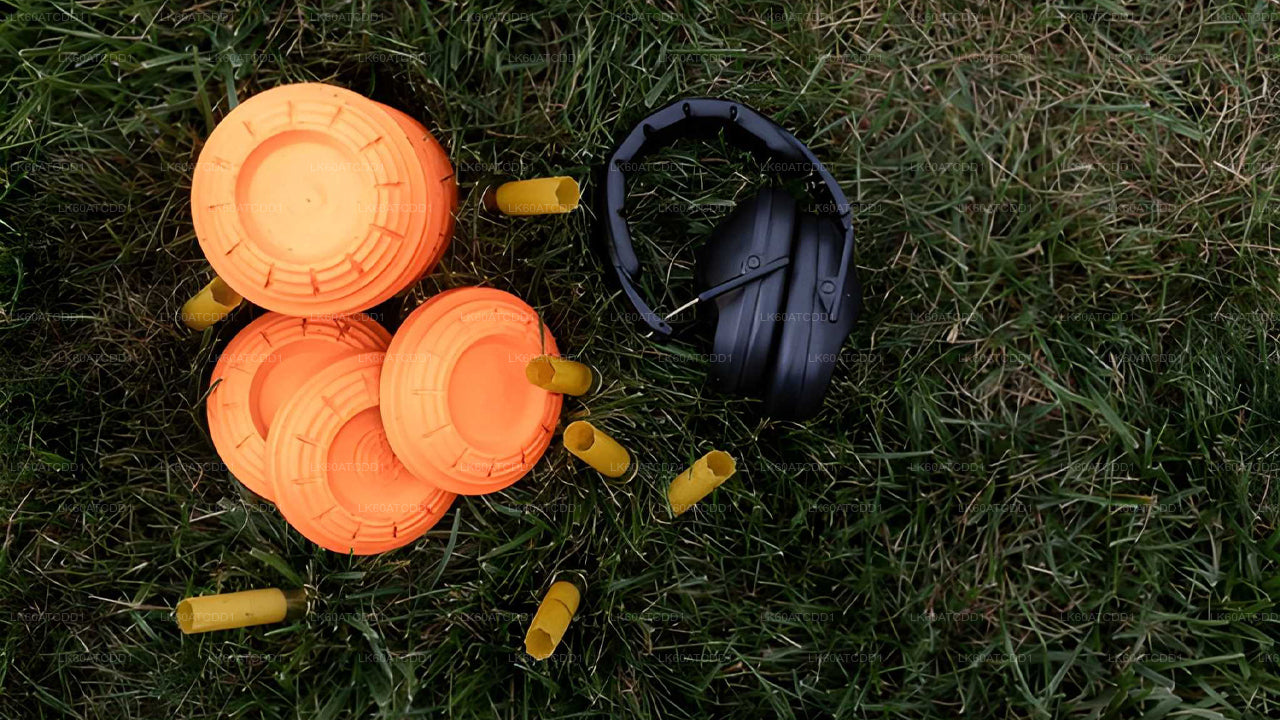 Orange clay targets and black ear protection on grass